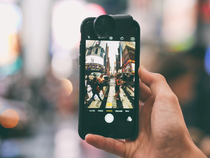 拿着智能手机的手拍一个繁忙的街道场面的照片